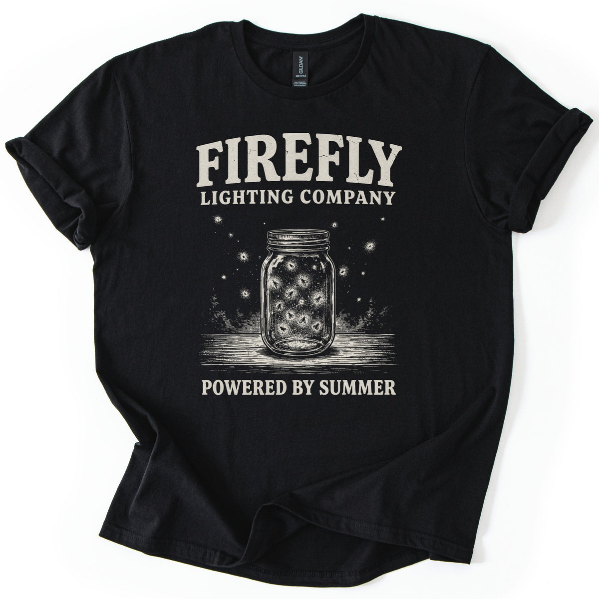 Firefly Lighting Company Comfort Colors T-shirt in Black, laid flat. Cream lettering reads Firefly Lighting Company over a drawing of a mason jar full of glowing fireflies, more drifting around it, and Powered by Summer below. Sleeves are rolled, on white.