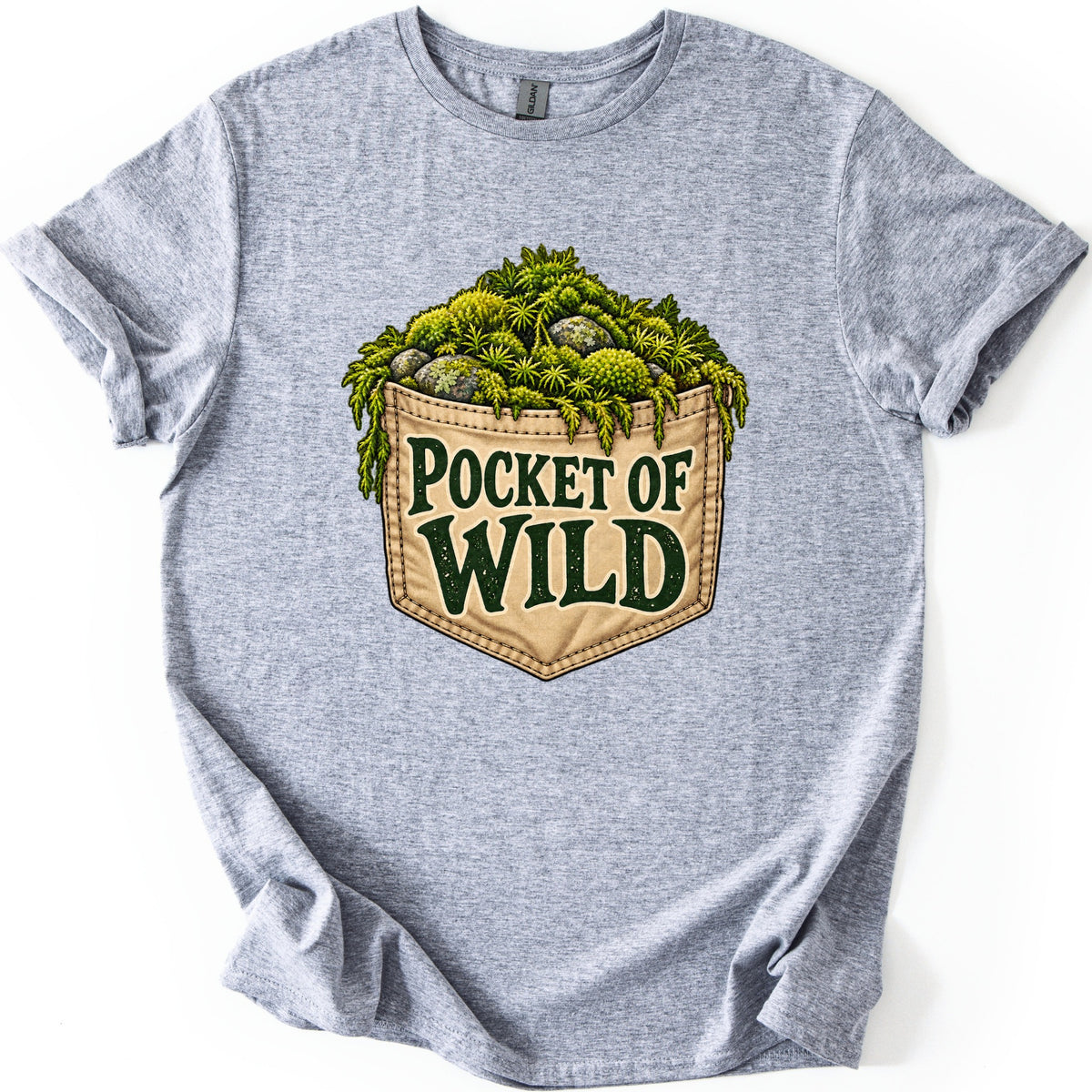 Pocket of Wild Comfort Colors T-shirt in Sport Grey, laid flat. A tan stitched pocket spills over with bright green moss and mossy gray stones, printed with the words Pocket of Wild in dark green. The shirt lies flat on white with rolled sleeves.