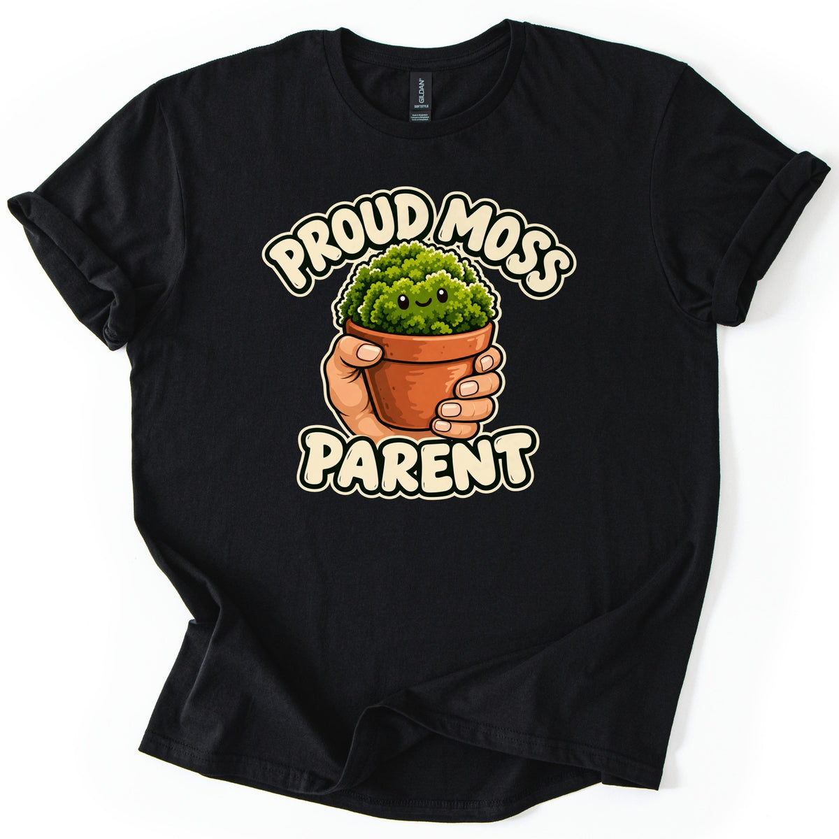 Proud Moss Parent Comfort Colors T-shirt in Black, laid flat. A cartoon hand holds a terracotta pot of smiling green moss between the words Proud Moss Parent in cream bubble letters. The shirt has cuffed sleeves and a folded hem on a white background.