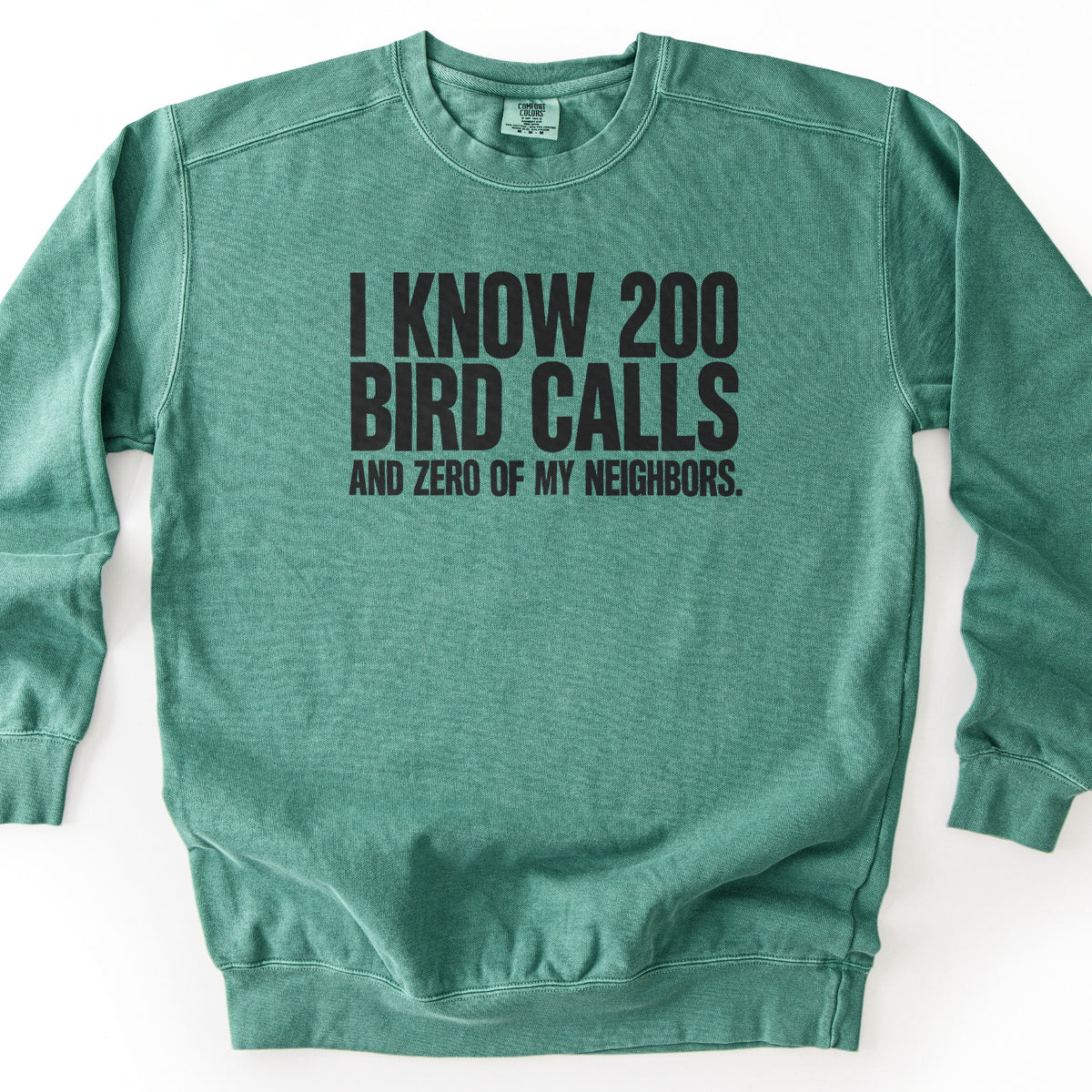 I Know 200 Bird Calls and Zero of My Neighbors Comfort Colors crewneck sweatshirt in Light Green, laid flat. Bold black capital letters across the chest read I Know 200 Bird Calls, with And Zero of My Neighbors. in smaller letters below. The sweatshirt lies on a plain white background.