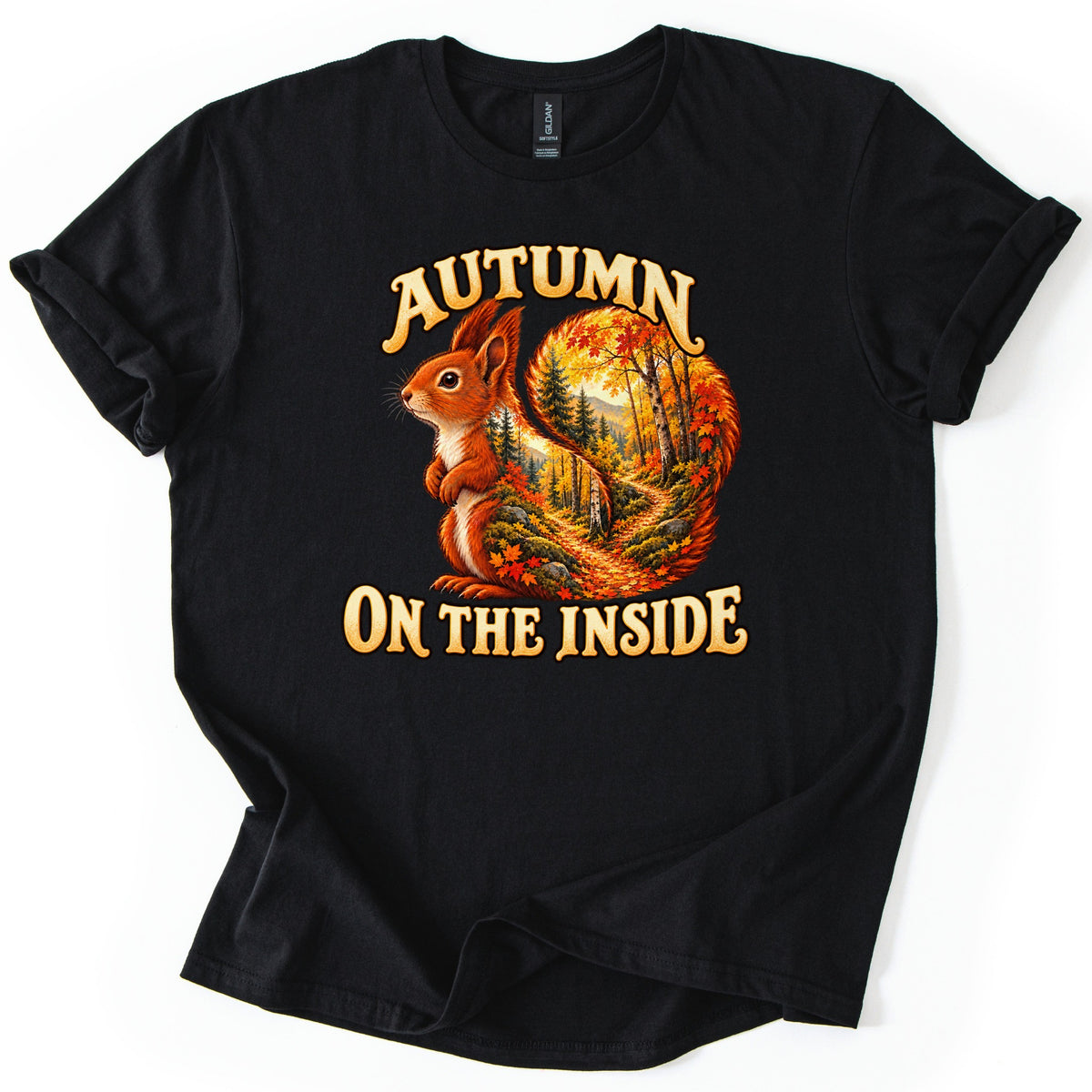 Autumn on the Inside Comfort Colors T-shirt in Black, laid flat. A red squirrel whose curled tail holds an autumn forest scene with a leaf-covered path sits between the words Autumn and On the Inside. The shirt has rolled sleeves on a white background.