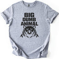 Big Dumb Animal Comfort Colors T-shirt in Sport Grey, laid flat. Bold black letters read BIG DUMB ANIMAL above a black illustration of a stern, front-facing bear head with shaggy fur. The sleeves are rolled and the shirt lies on a white background.