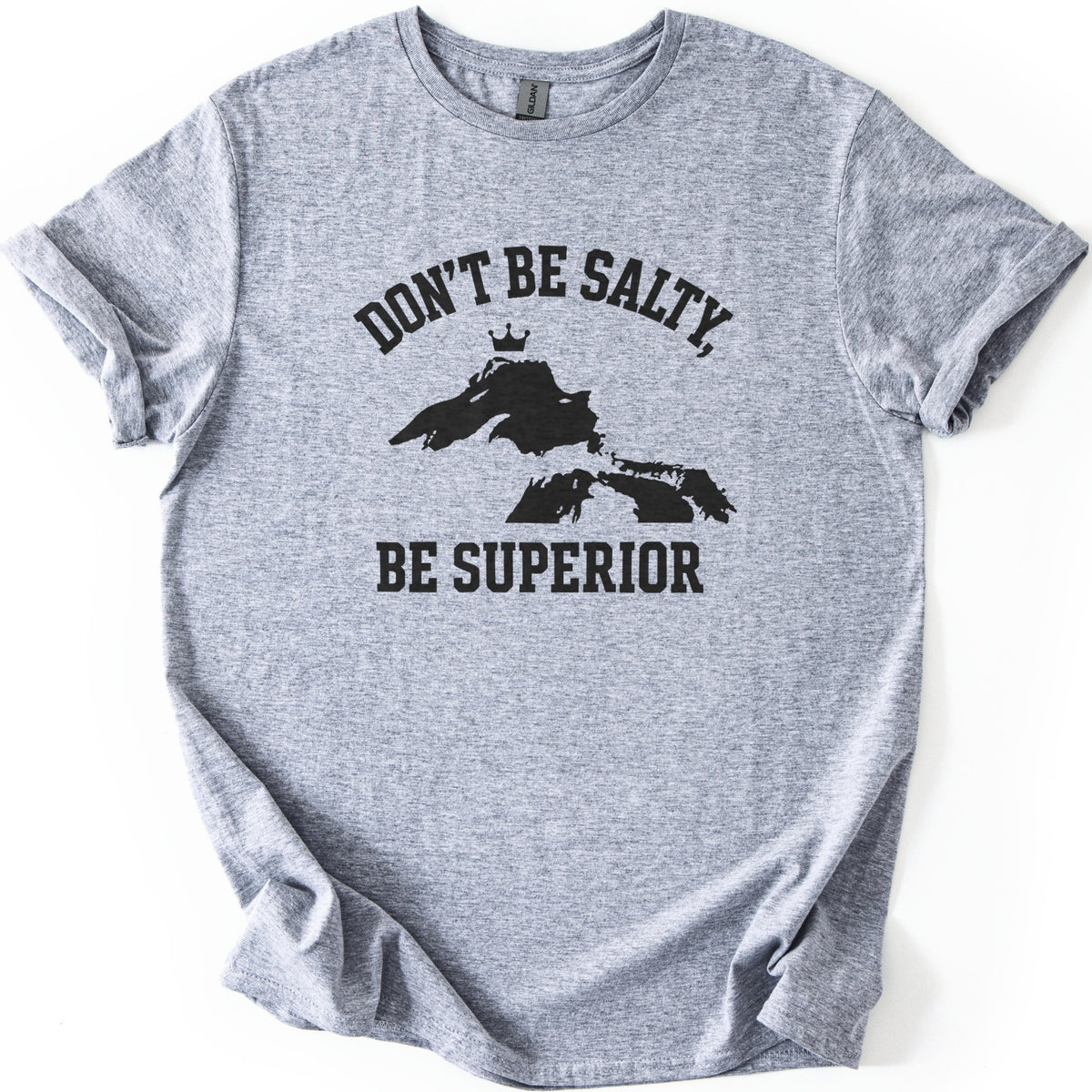 Be Superior Comfort Colors T-shirt in Sport Grey, laid flat. A black print shows the words Don't Be Salty, arched over a silhouette of the Great Lakes with a small crown above Lake Superior, and Be Superior below. Sleeves are cuffed on a white background.