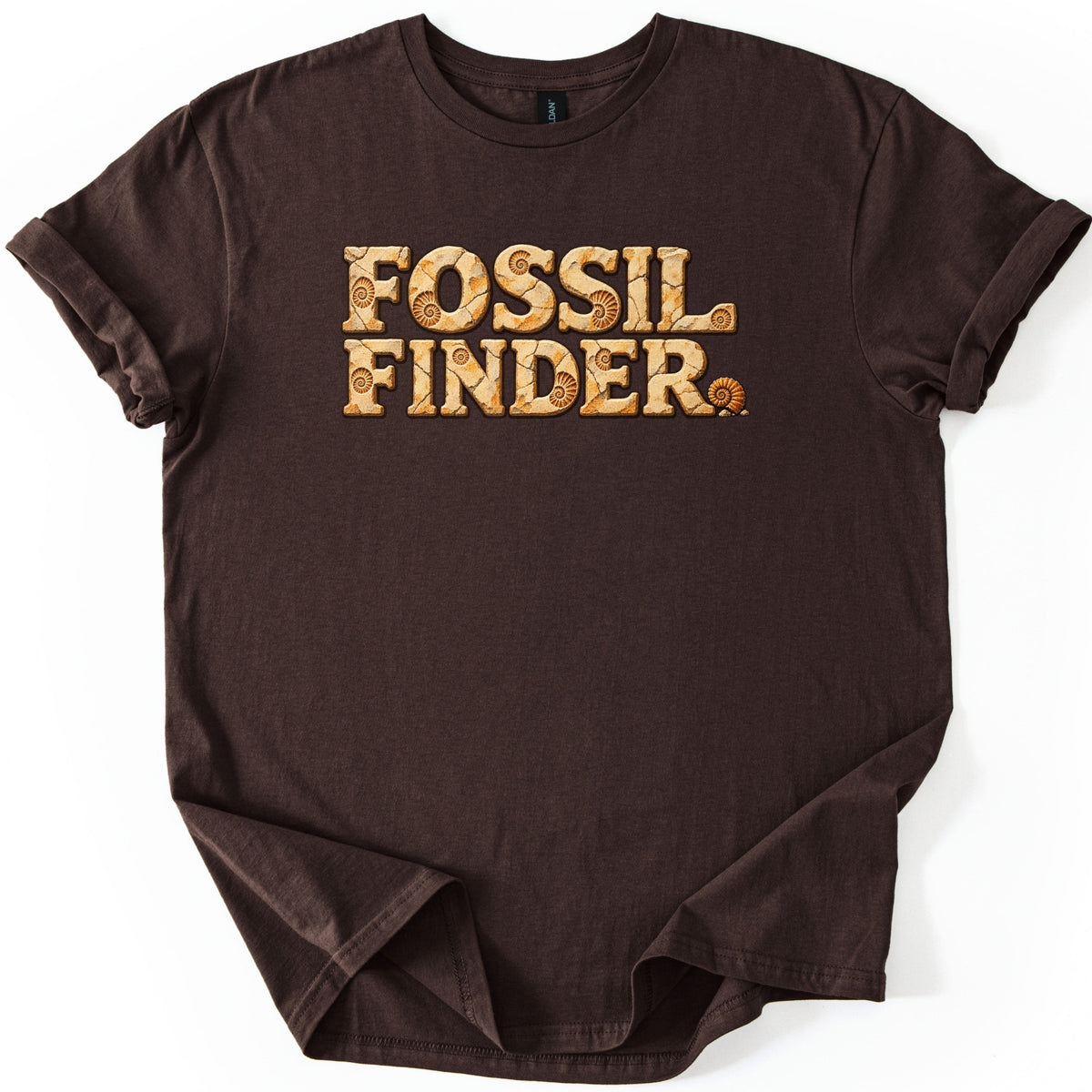 Fossil Finder Comfort Colors T-shirt in Dark Chocolate, laid flat. The words Fossil Finder in chunky cracked tan stone letters with ammonite fossil imprints, and a small ammonite shell as the period. The shirt has cuffed sleeves and a folded hem on a white background.