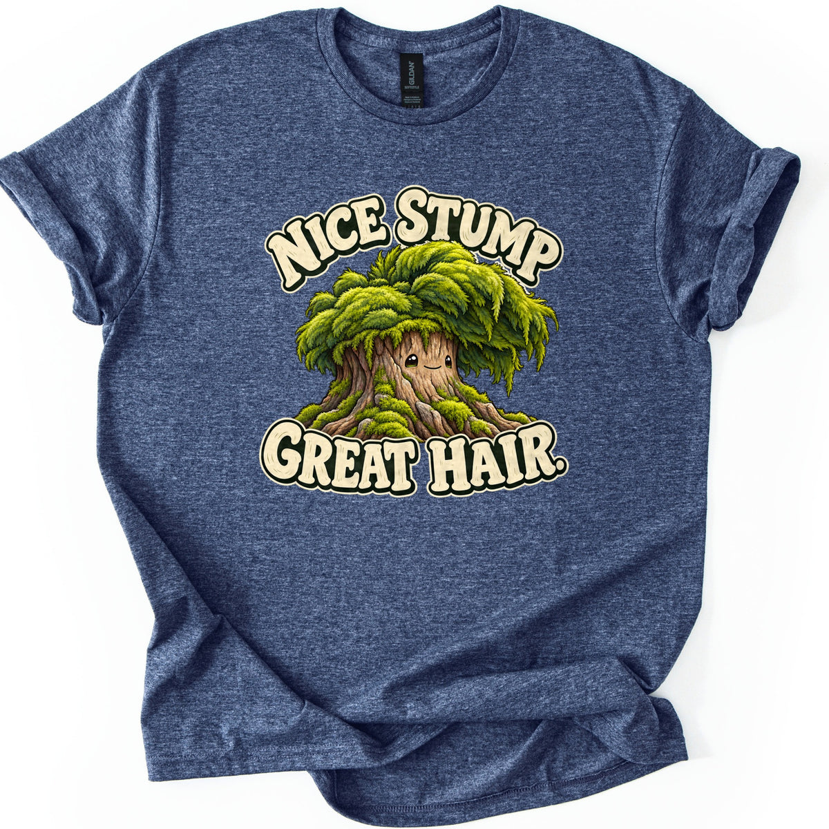 Nice Stump Great Hair Comfort Colors T-shirt in Heather Navy, laid flat. A smiling cartoon tree stump with a thick mop of green moss like hair, between the words Nice Stump and Great Hair. in cream letters. The shirt has rolled sleeves and lies on a white background.