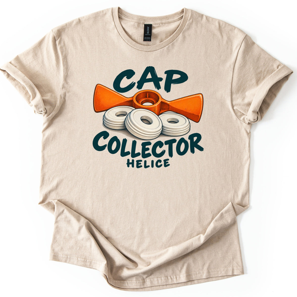 Cap Collector Comfort Colors T-shirt in Sand, laid flat. The words Cap Collector in dark green brush letters surround an orange propeller-shaped tool and three white ringed discs, with Helice printed below. Sleeves are rolled on a white background.