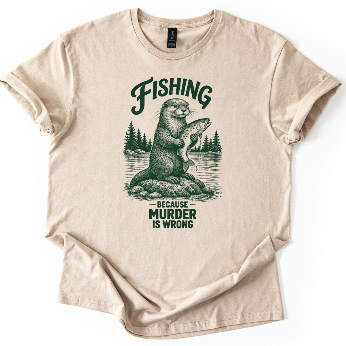 Fishing Murder Otter Comfort Colors T-shirt in Sand, laid flat. A sketched otter sits on a rock in a lake holding a dripping trout, with pine trees behind it, under the word Fishing and above Because Murder Is Wrong in dark green ink. Cuffed sleeves, white background.