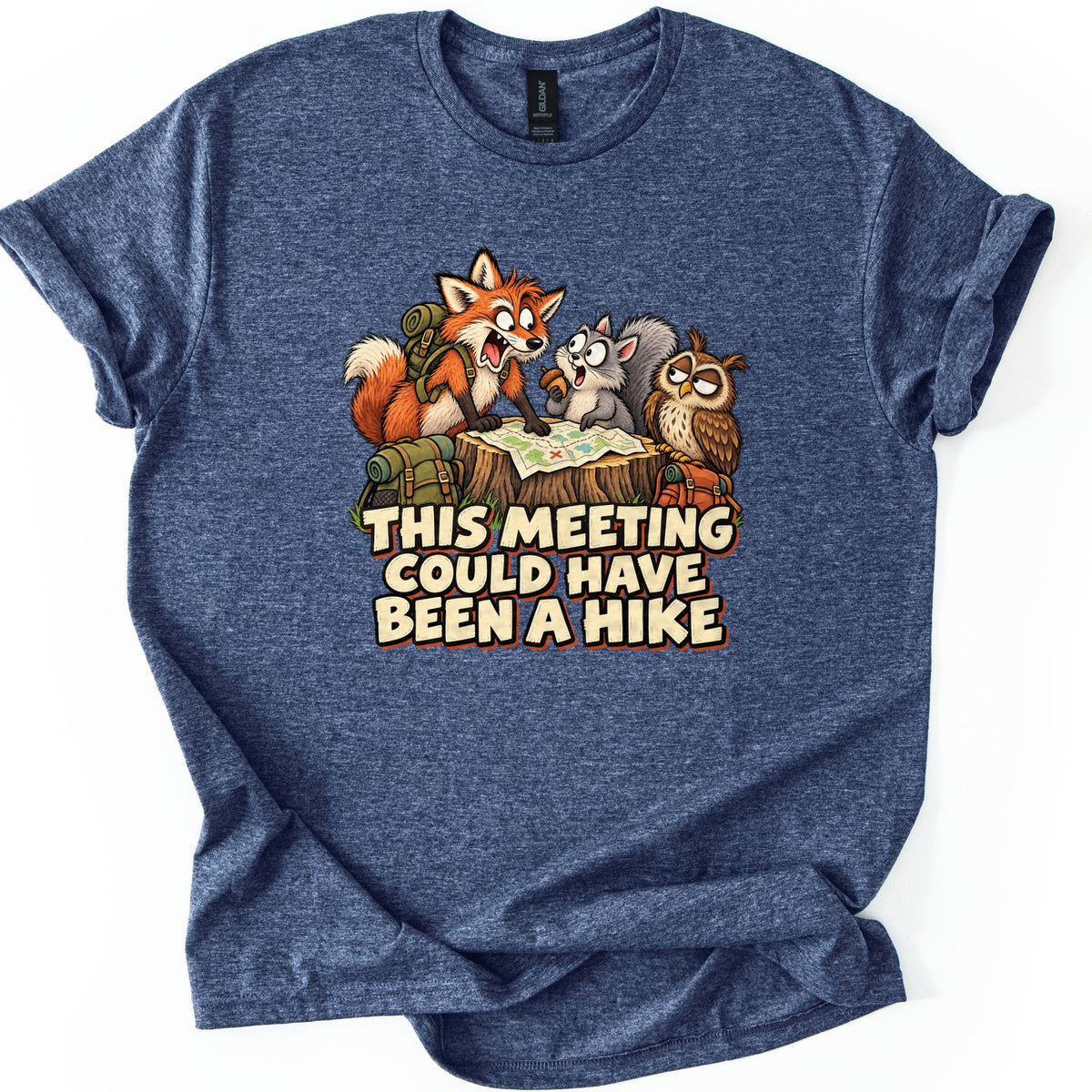 This Meeting Could Have Been a Hike Comfort Colors T-shirt in Heather Navy, laid flat. A cartoon fox, gray squirrel and owl study a map on a tree stump surrounded by backpacks, above the words This Meeting Could Have Been a Hike. The shirt has rolled sleeves on a white background.