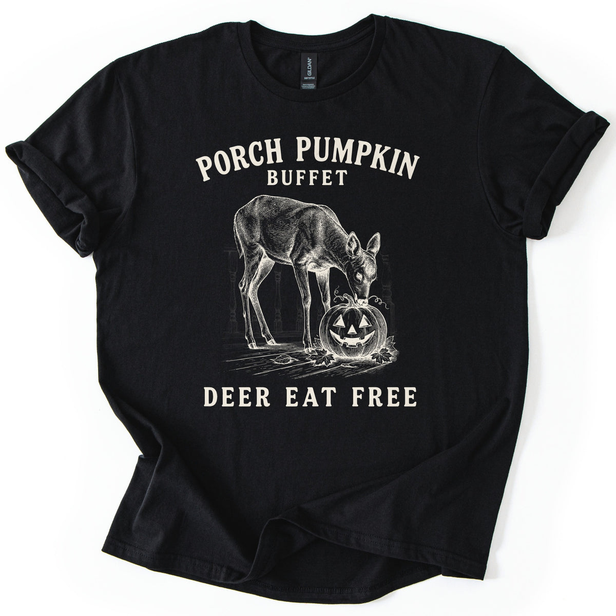 Porch Pumpkin Buffet Comfort Colors T-shirt in Black, laid flat. A cream engraving-style drawing of a deer nibbling a carved jack-o'-lantern on a porch with fallen leaves, between the words Porch Pumpkin Buffet and Deer Eat Free. Sleeves are rolled, on a white background.