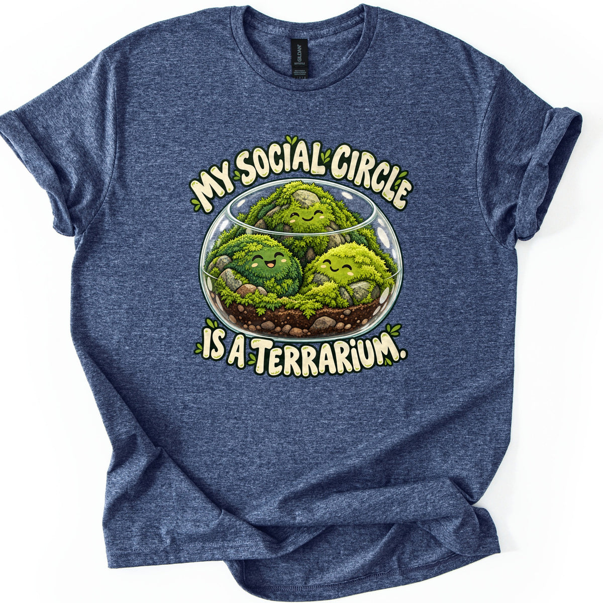 My Social Circle Is a Terrarium Comfort Colors T-shirt in Heather Navy, laid flat. Three happy moss balls rest among rocks in a round glass terrarium, with My Social Circle arched above and Is a Terrarium. below in cream lettering. The shirt is shown on a white background with rolled sleeves.
