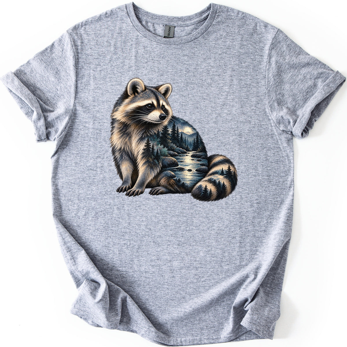 Raccoon Night Creek Comfort Colors T-shirt in Sport Grey, laid flat. A realistic raccoon sits gazing sideways, a moonlit forest creek with pine trees and mountains blended into its fur and ringed tail. No words. The shirt has cuffed sleeves and lies on a white background.