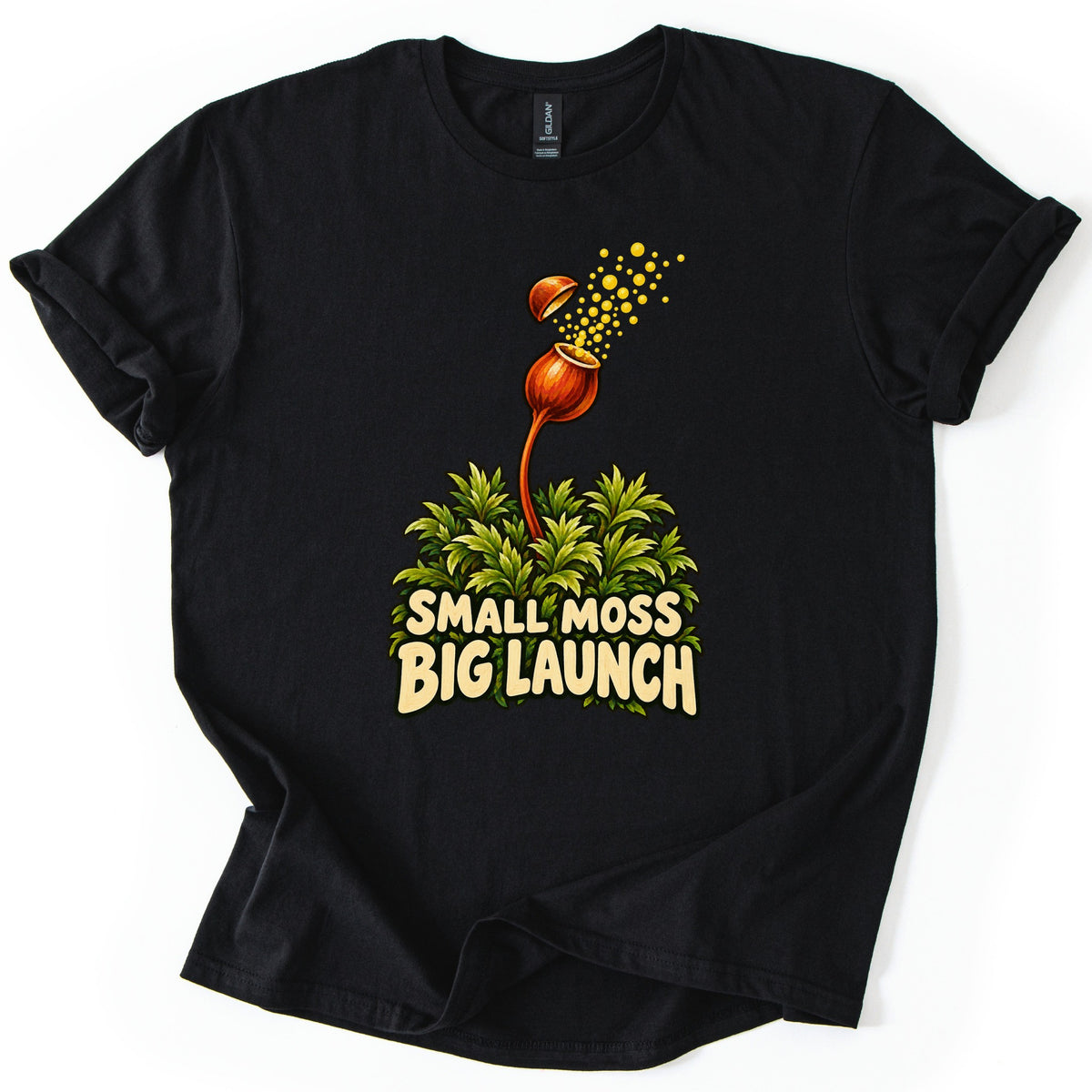 Small Moss Big Launch Comfort Colors T-shirt in Black, laid flat. An orange moss capsule on a curved stalk rises from leafy green moss, its lid popping off as yellow spores burst out, above the words Small Moss Big Launch. Rolled sleeves, on a white background.