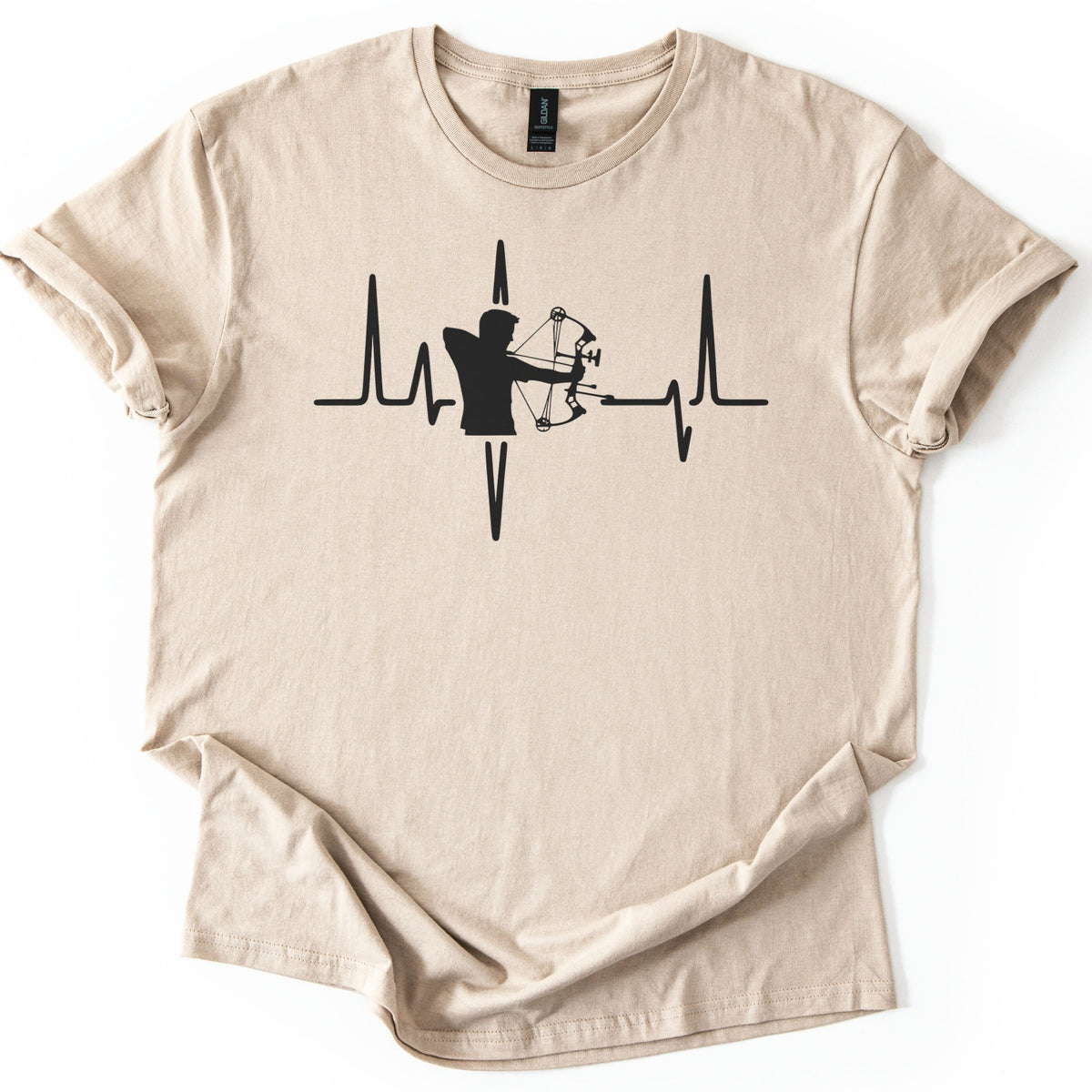 Compound Bow Archer Comfort Colors T-shirt in Sand, laid flat. A black silhouette of an archer drawing a compound bow sits in the middle of a heartbeat line across the chest, with no words. The shirt lies on a white background with its sleeves cuffed.