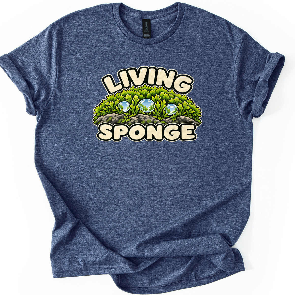 Living Sponge Comfort Colors T-shirt in Heather Navy, laid flat. A cartoon clump of green moss on gray stones with three glassy water droplets sits between the words LIVING and SPONGE in cream bubble letters. Shown on a white background with cuffed sleeves.