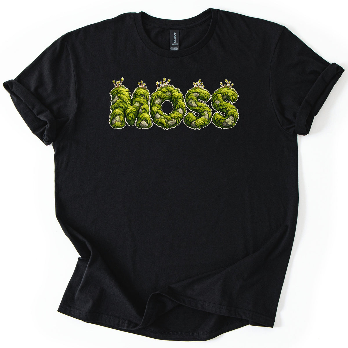 Moss Comfort Colors T-shirt in Black, laid flat. Bright green moss-covered letters spell MOSS across the chest, with gray stones and thin sprouts on top and a light outline. The shirt has cuffed sleeves and lies on a white background.