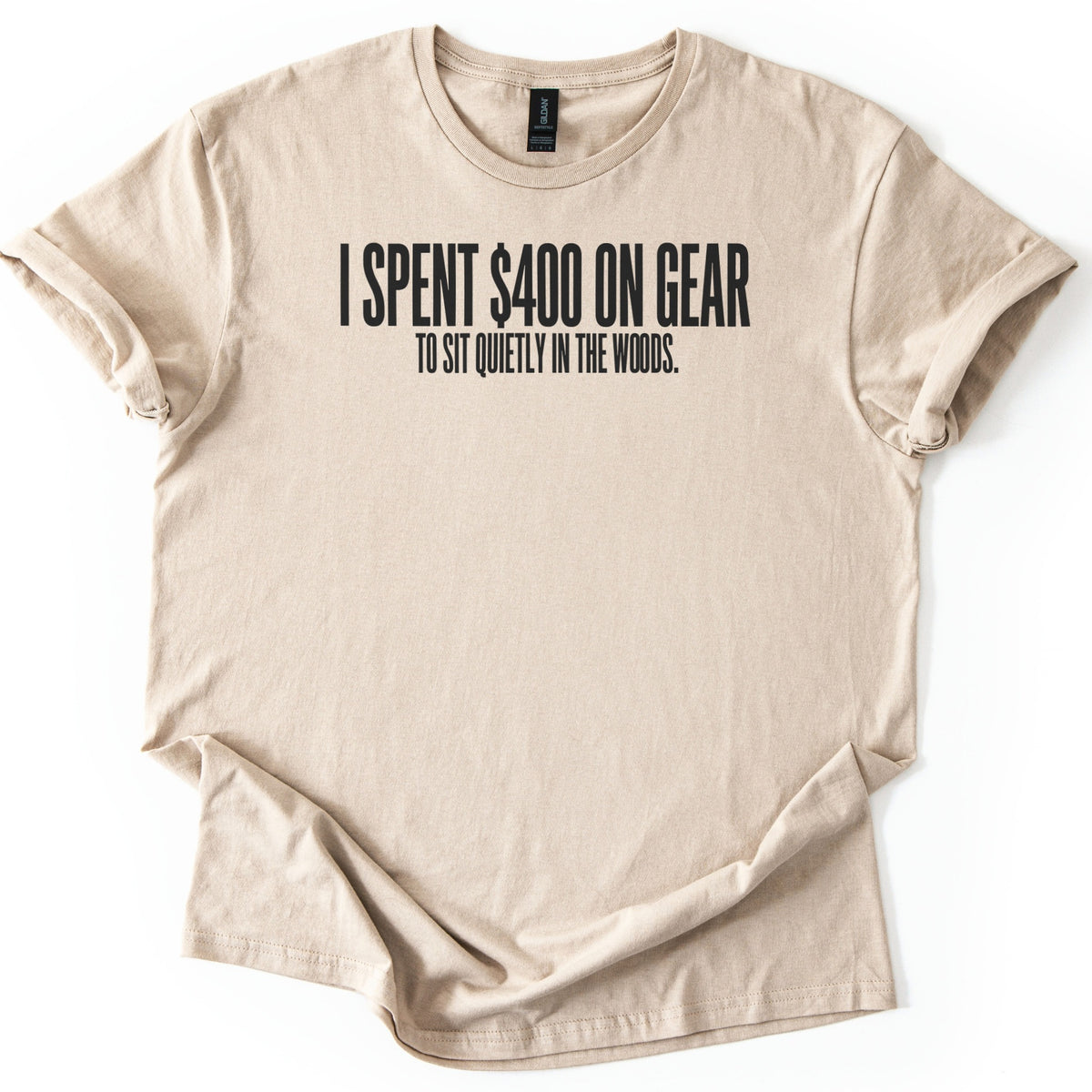 Gear To Sit Quietly Comfort Colors T-shirt in Sand, laid flat. Black block letters across the chest read I SPENT $400 ON GEAR, with TO SIT QUIETLY IN THE WOODS. in smaller letters below. The shirt has rolled sleeves and lies on a white background.