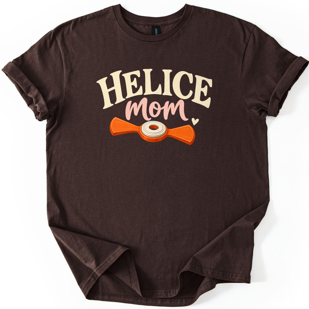 Helice Mom Comfort Colors T-shirt in Dark Chocolate, laid flat. Cream arched letters read HELICE above pink script reading mom with a small heart, over an orange two-bladed helice target with a cream center ring. The shirt has rolled sleeves on a white background.