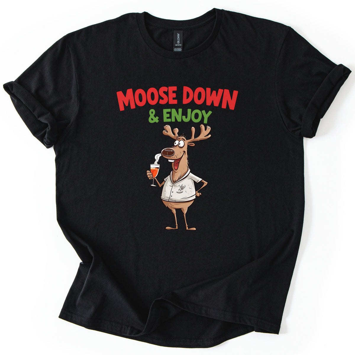 Moose Down And Enjoy Comfort Colors T-shirt in Black, laid flat. Red words Moose Down above green & Enjoy, over a grinning cartoon moose in a white short-sleeve shirt holding a glass of orange drink, hand on hip. Sleeves are cuffed on a white background.