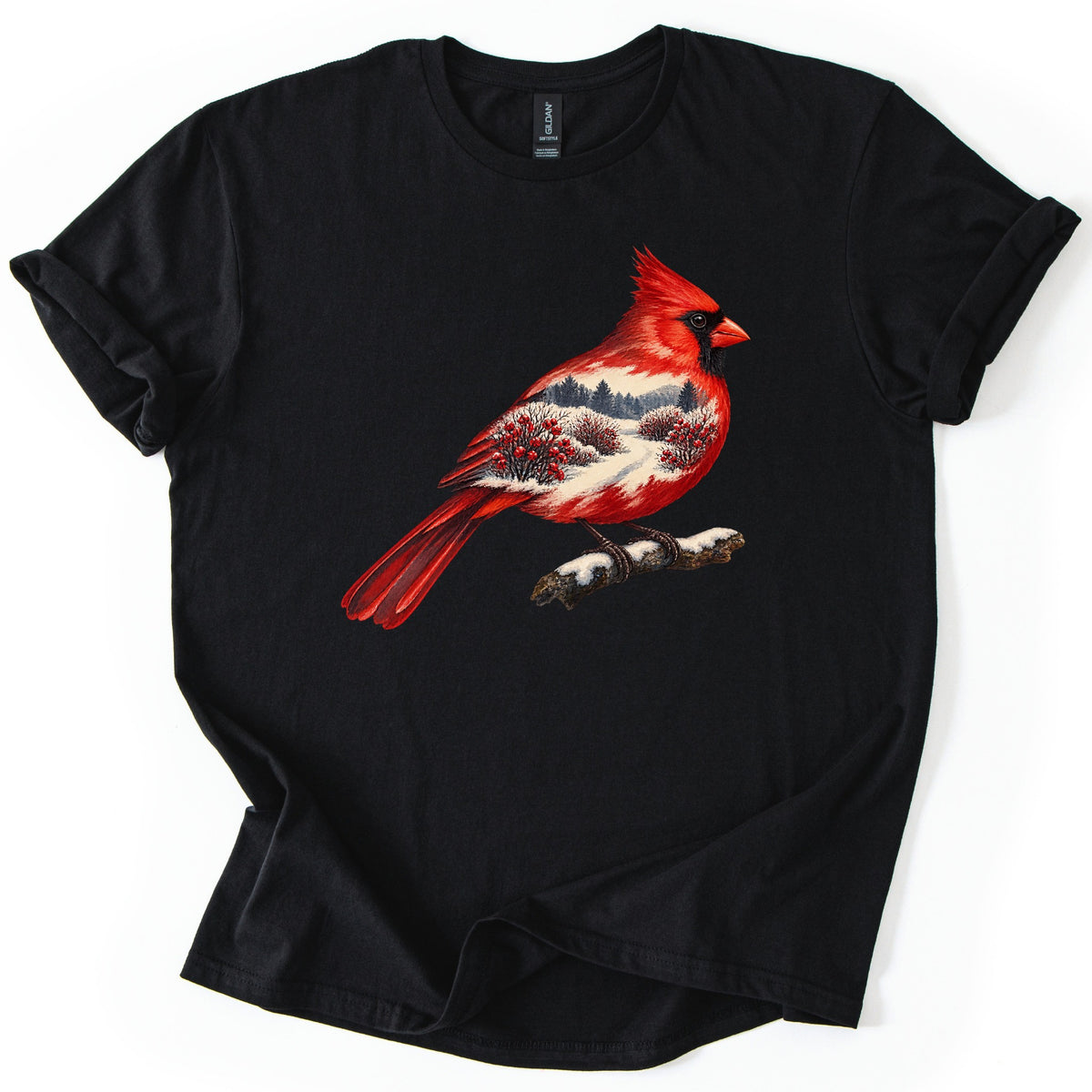 Winter Cardinal Comfort Colors T-shirt in Black, laid flat. A painted red cardinal perches on a snowy branch, its body filled with a winter scene of evergreens, a snowy path and red-berry bushes. No words are printed. The sleeves are cuffed on a white background.