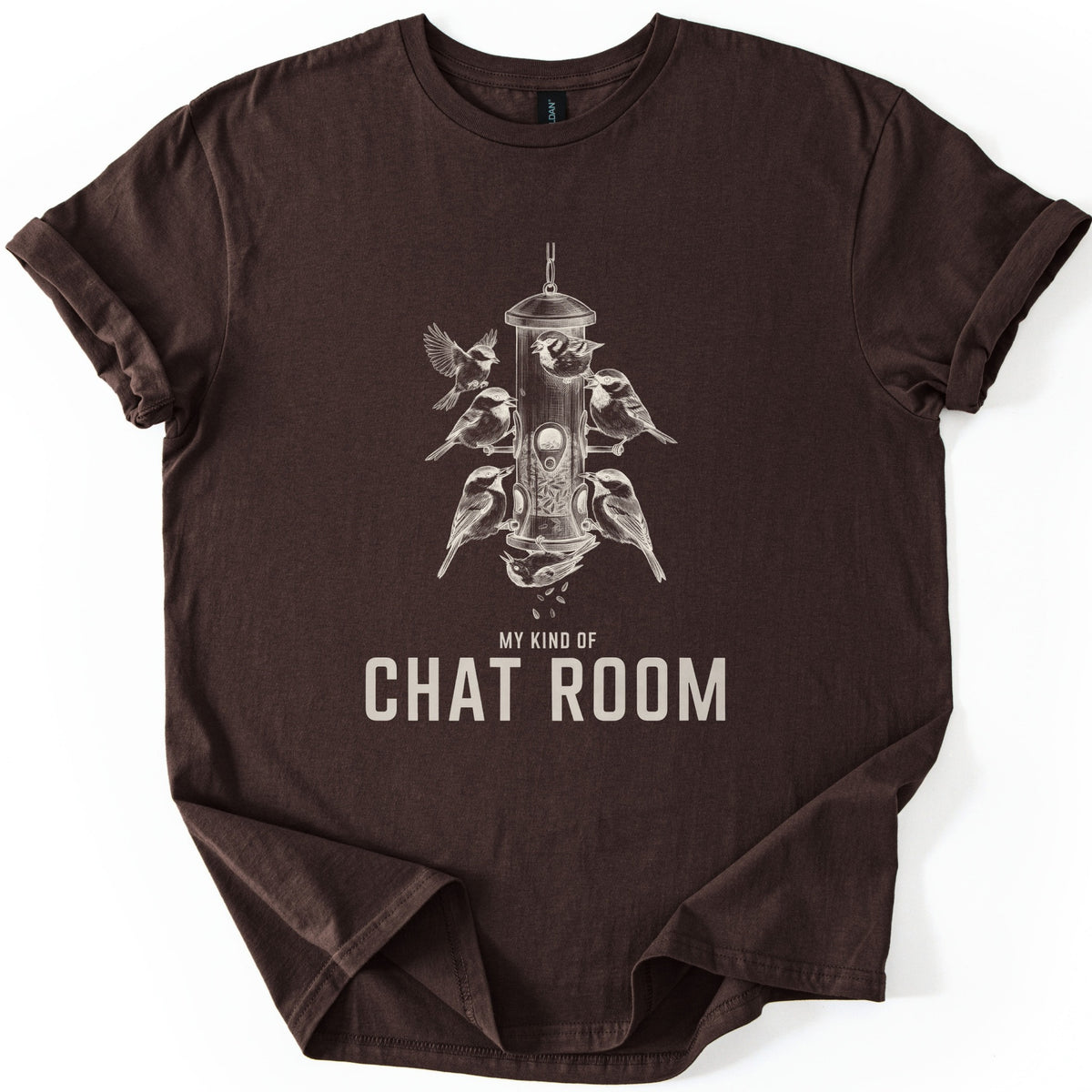 My Kind Of Chat Room Comfort Colors T-shirt in Dark Chocolate, laid flat. A cream sketch of chickadees and sparrows perched around a hanging tube bird feeder, one upside down below spilling seeds, above the words My Kind Of Chat Room. Sleeves rolled, on a white background.