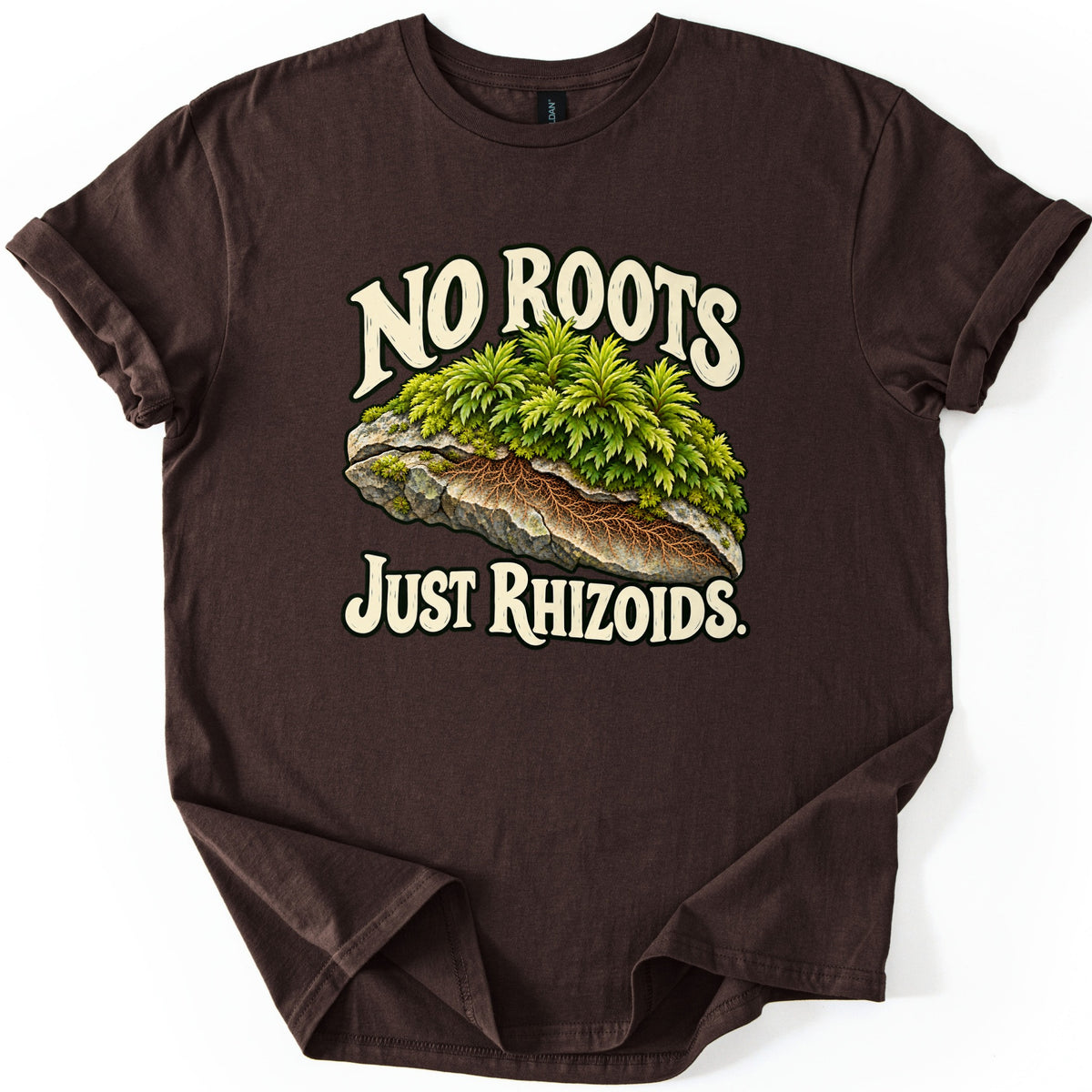 No Roots Just Rhizoids Comfort Colors T-shirt in Dark Chocolate, laid flat. A clump of green moss on a gray rock, cut away to reveal brown threadlike rhizoids, sits between cream words reading No Roots and Just Rhizoids. The shirt lies on a white background with cuffed sleeves.