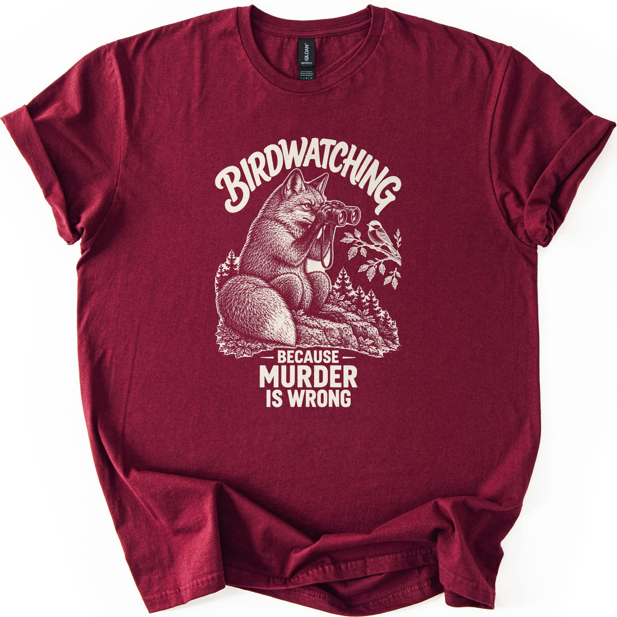 Birdwatching Murder Fox Comfort Colors T-shirt in Maroon, laid flat. A sketched fox sits on a rock peering through binoculars at a chickadee on a branch, with Birdwatching arched above and Because Murder Is Wrong below, in cream ink. On a white surface, sleeves cuffed.