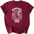 Aromatherapy Murder Skunk Comfort Colors T-shirt in Maroon, laid flat. A cream skunk sniffs a lavender bundle beside a basket, flowers and an oil bottle, under the word Aromatherapy and above Because Murder Is Wrong. Sleeves are cuffed on a white background.