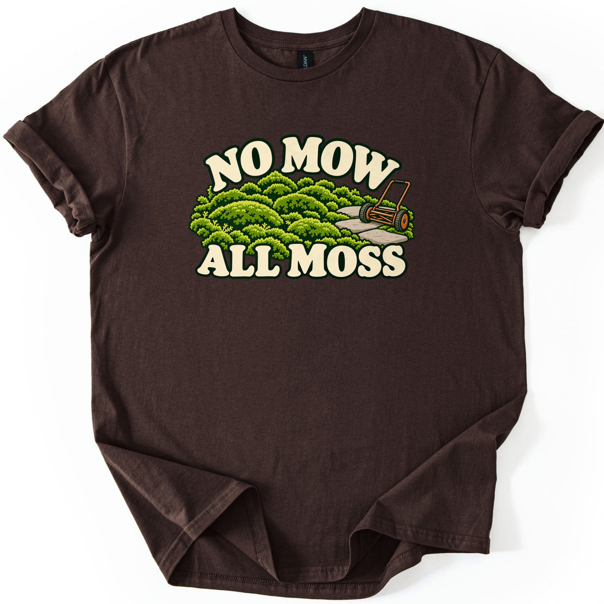 No Mow All Moss Comfort Colors T-shirt in Dark Chocolate, laid flat. Cream retro letters read No Mow above a cartoon of mounded green moss, a stone path and an old push reel mower, with All Moss below. The shirt lies on a white surface with cuffed sleeves.