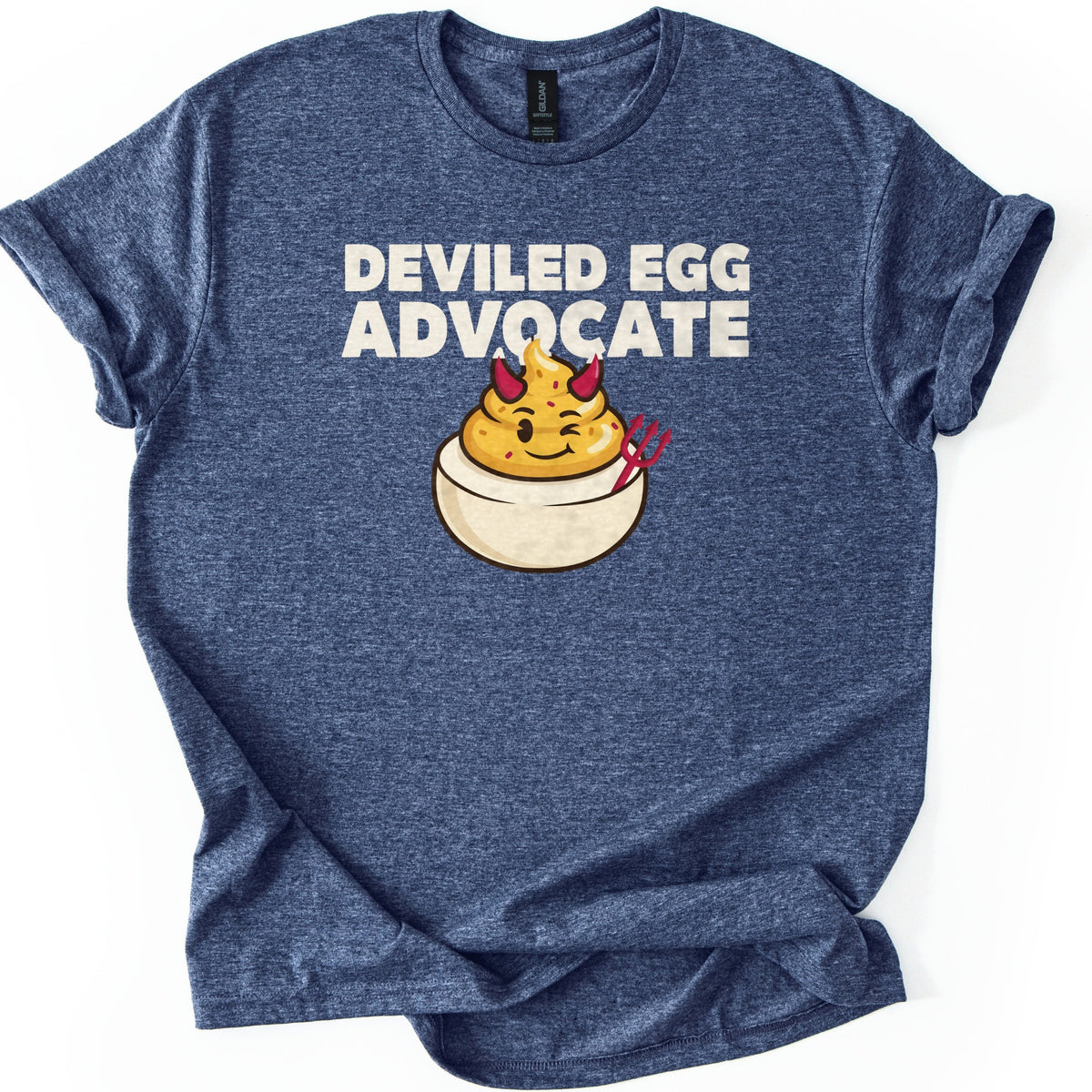 Deviled Egg Advocate Comfort Colors T-shirt in Heather Navy, laid flat. Bold cream text reads Deviled Egg Advocate above a cartoon deviled egg with red devil horns, a wink, and a small red pitchfork. The shirt has cuffed sleeves and lies on a white background.