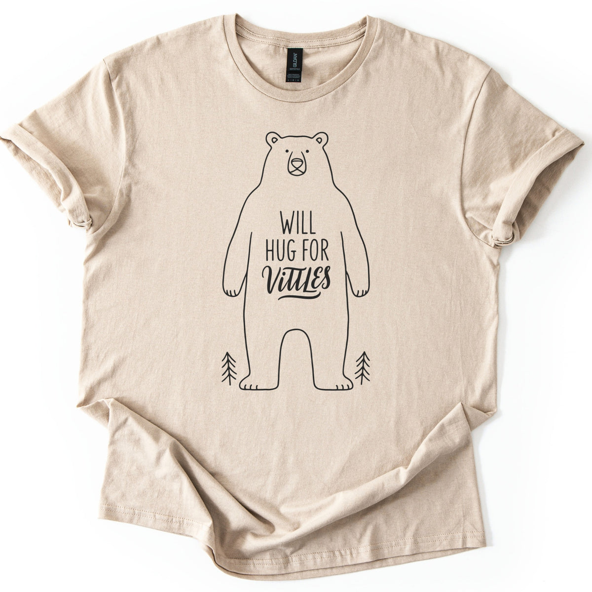 Will Hug For Vittles Bear Comfort Colors T-shirt in Sand, laid flat. A black line drawing of a standing bear with the words WILL HUG FOR Vittles on its belly and a small pine tree at each foot. The shirt has rolled sleeves and lies on a white background.