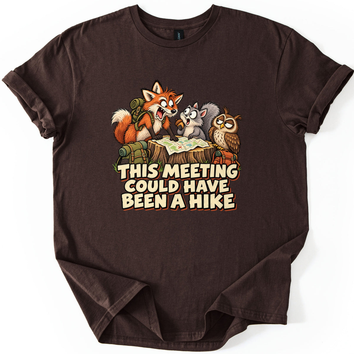 This Meeting Could Have Been a Hike Comfort Colors T-shirt in Dark Chocolate, laid flat. A wide-eyed cartoon fox, a squirrel holding an acorn and a drowsy owl look over a map on a tree stump above the words This Meeting Could Have Been a Hike. The shirt lies on a white background.