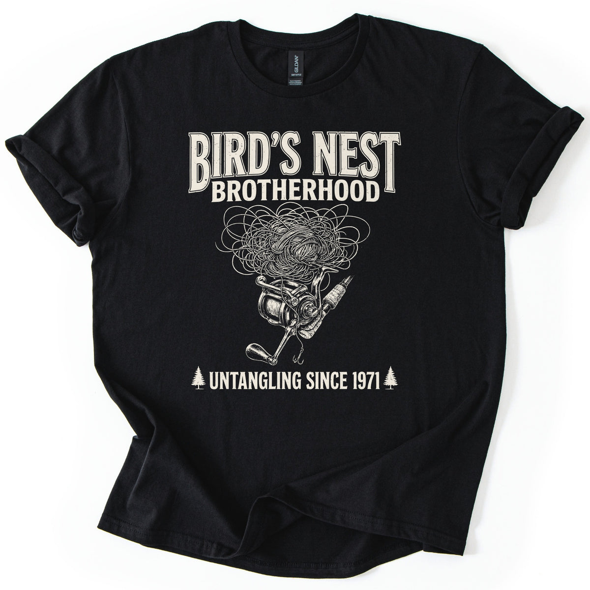 Birds Nest Brotherhood Comfort Colors T-shirt in Black, laid flat. Cream print reads Bird's Nest Brotherhood above a tangled mess of fishing line over a spinning reel, rod and hook, then Untangling Since 1971 between two pine trees. Sleeves cuffed, on a white backdrop.