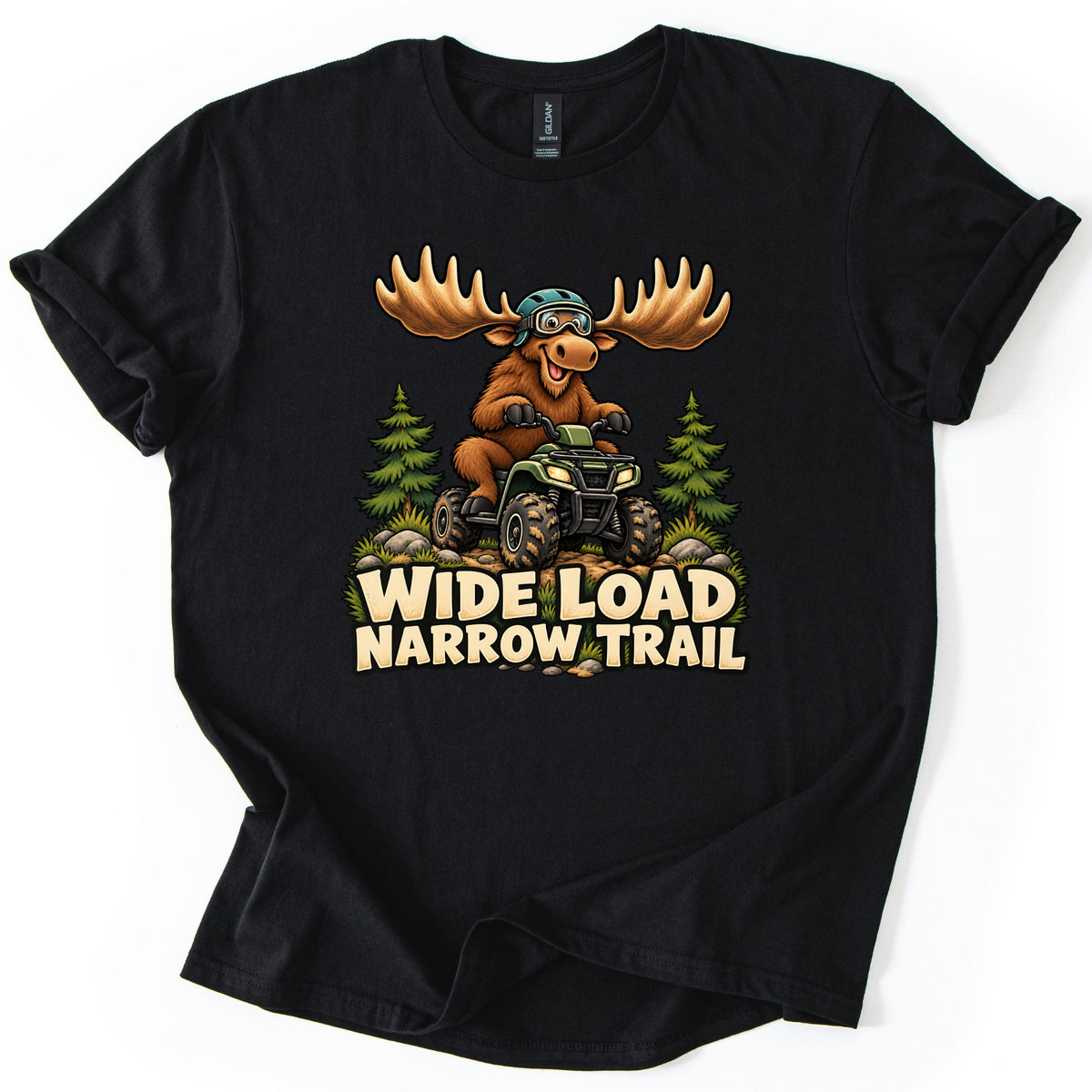 Wide Load Narrow Trail Comfort Colors T-shirt in Black, laid flat. A cartoon moose with huge antlers, a helmet and goggles rides a green ATV on a dirt trail between pine trees above the words Wide Load Narrow Trail. The shirt lies on a white background with cuffed sleeves.