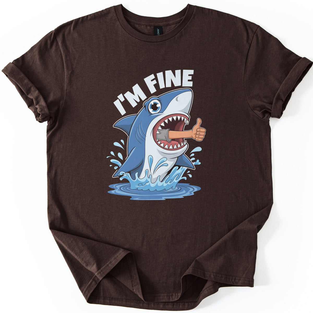 Shark I'm Fine Comfort Colors T-shirt in Dark Chocolate, laid flat. A cartoon blue shark leaps from splashing water with a human arm giving a thumbs up sticking out of its open mouth, under the words I'M FINE in white. The shirt has rolled sleeves on a white background.