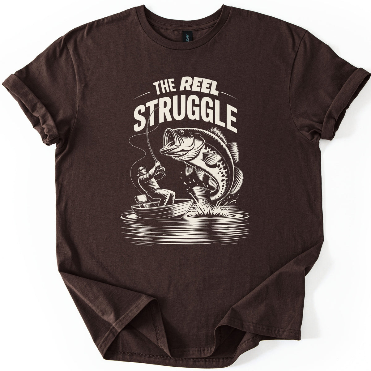 Reel Struggle Comfort Colors T-shirt in Dark Chocolate, laid flat. Cream print of the words The Reel Struggle above a fisherman in a small boat pulling back on a bent rod as a large bass leaps from the water. The sleeves are rolled, on a white background.