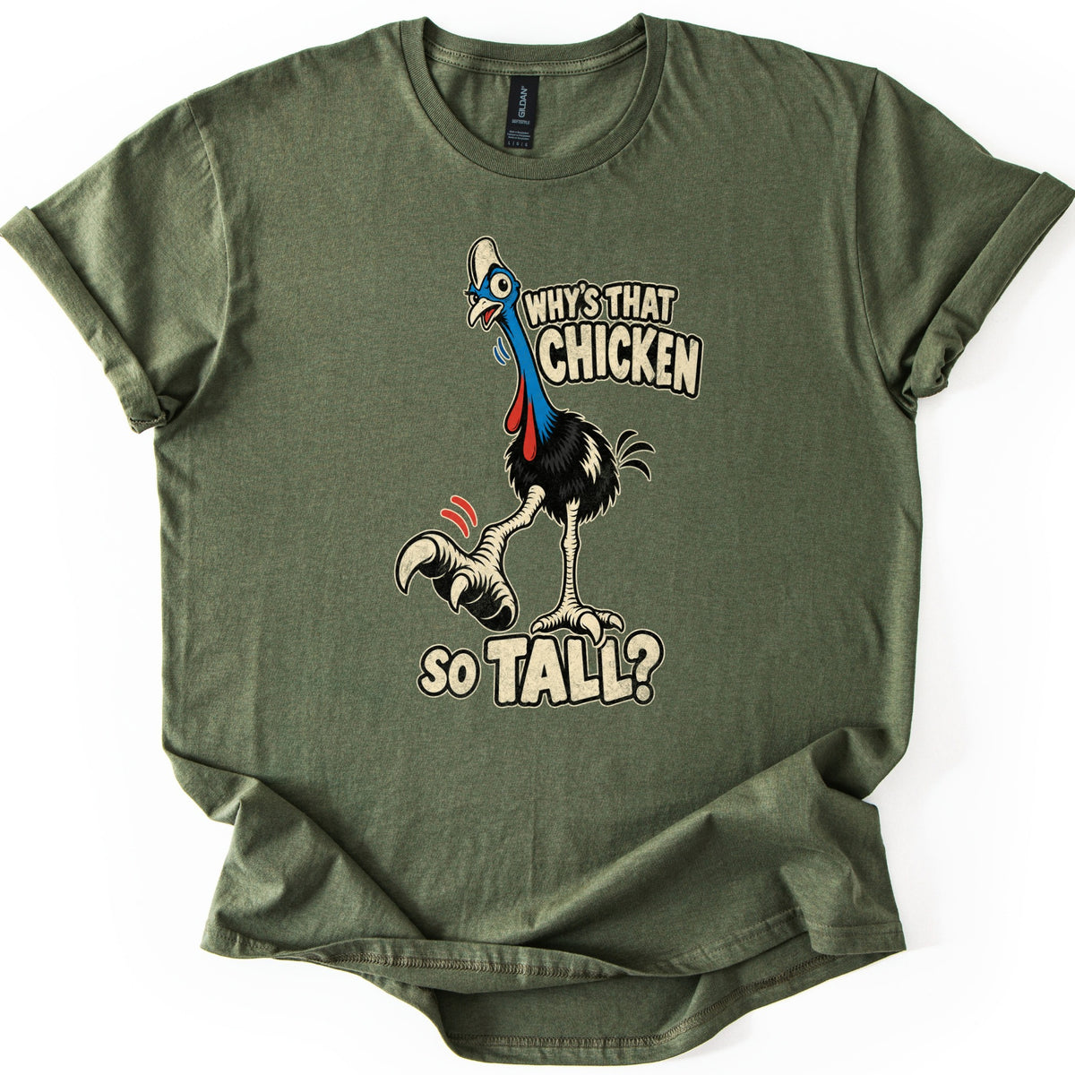 Why's That Chicken So Tall Comfort Colors T-shirt in Military Green, laid flat. A startled cartoon cassowary with a blue neck, red wattles and black feathers lifts one clawed foot under cream words reading Why's That Chicken So Tall? The shirt lies on white with cuffed sleeves.