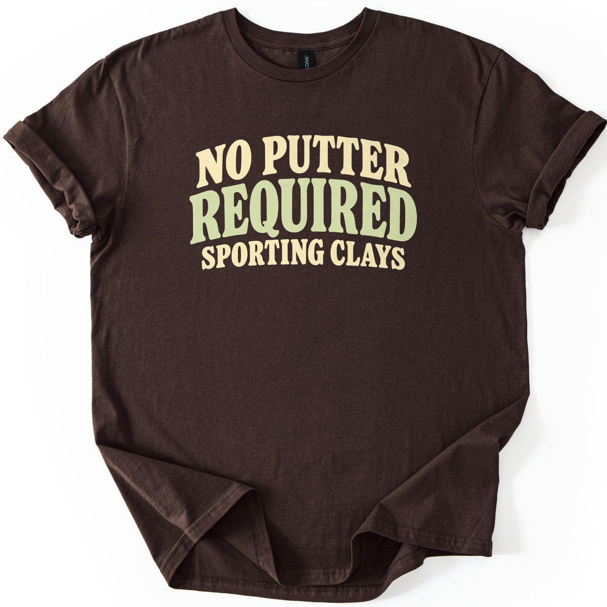 No Putter Required Comfort Colors T-shirt in Dark Chocolate, laid flat. Wavy retro letters read NO PUTTER in cream, REQUIRED in larger sage green, and SPORTING CLAYS in cream below. The shirt lies on a white background with rolled sleeves and a slightly folded hem.
