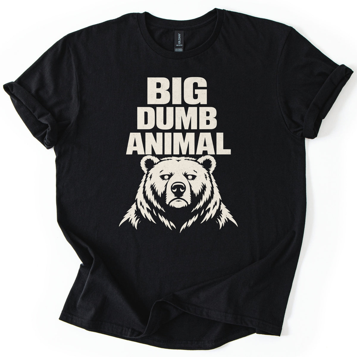 Big Dumb Animal Comfort Colors T-shirt in Black, laid flat. Bold cream letters read BIG DUMB ANIMAL above a cream illustration of a stern, front-facing bear head with shaggy fur. The sleeves are rolled and the shirt lies on a white background.