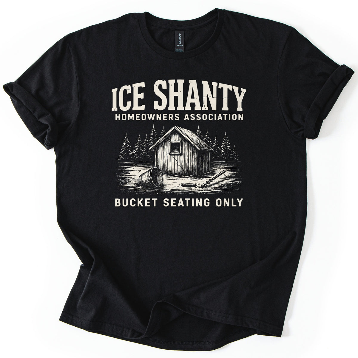 Ice Shanty Homeowners Association Comfort Colors T-shirt in Black, laid flat. Cream print reads ICE SHANTY, HOMEOWNERS ASSOCIATION above a sketch of a wooden ice shack among pines with a tipped bucket, ice hole and auger, then BUCKET SEATING ONLY. Sleeves cuffed, on white.