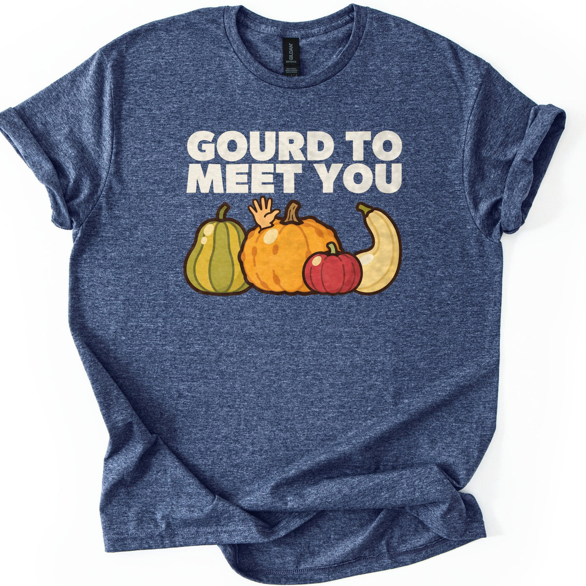 Gourd To Meet You Comfort Colors T-shirt in Heather Navy, laid flat. Cream block letters read GOURD TO MEET YOU over a row of cartoon gourds, with a small hand waving from behind the big orange pumpkin beside a green squash, red pumpkin and cream squash. Sleeves cuffed, on white.