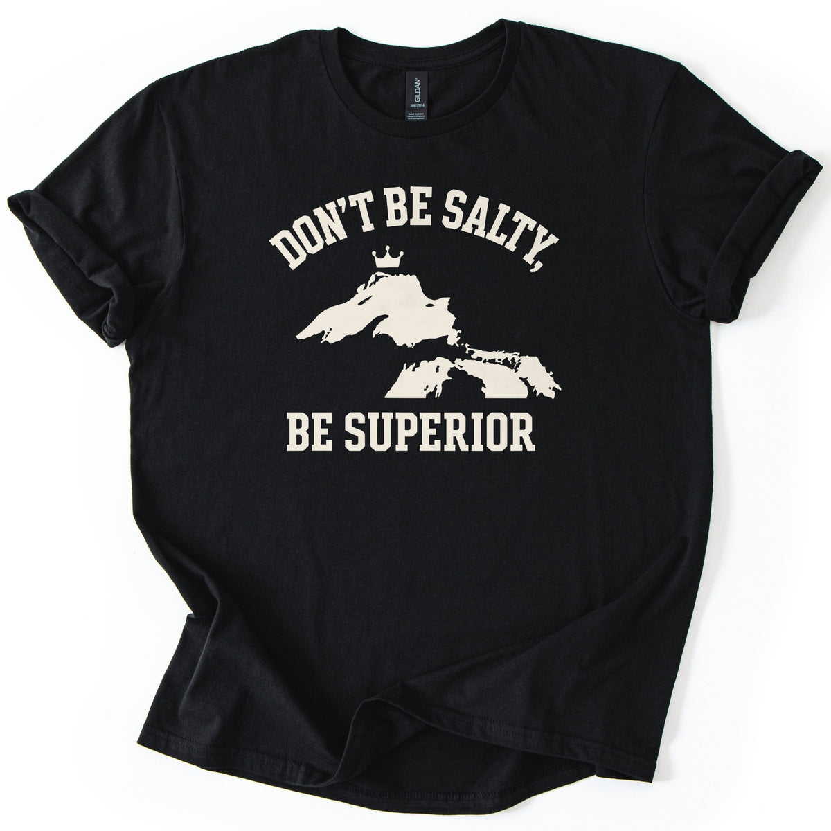 Be Superior Comfort Colors T-shirt in Black, laid flat. A cream print shows the words Don't Be Salty, arched over a silhouette of the Great Lakes with a small crown above Lake Superior, and Be Superior below. Sleeves are cuffed on a white background.