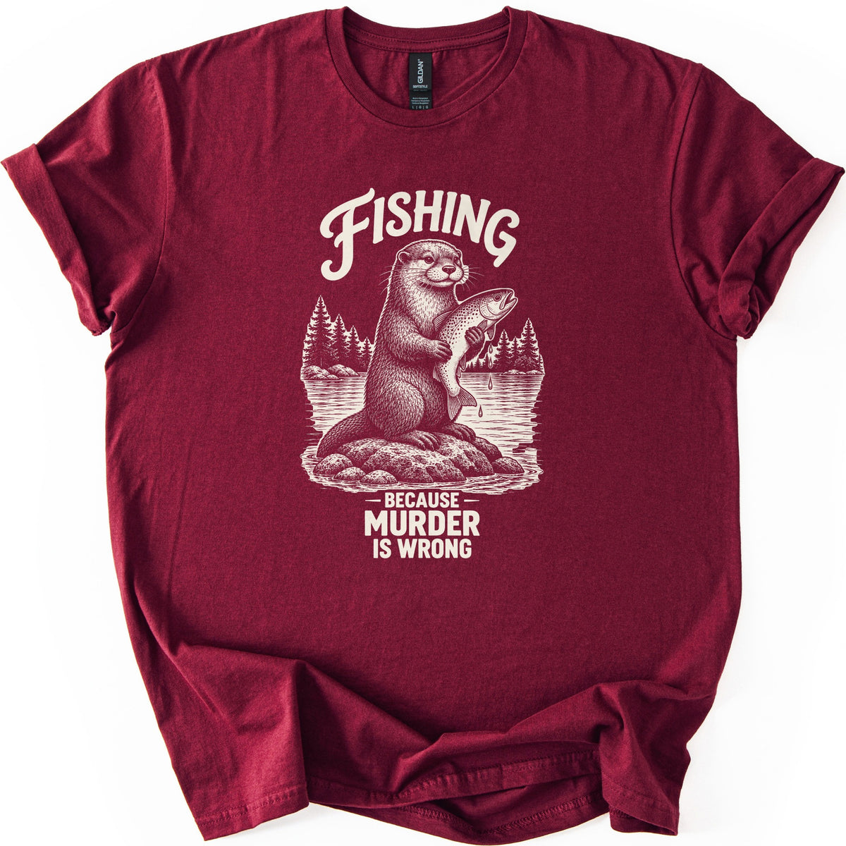 Fishing Murder Otter Comfort Colors T-shirt in Maroon, laid flat. A sketched otter sits on a rock in a lake holding a dripping trout, with pine trees behind it, under the word Fishing and above Because Murder Is Wrong in cream ink. Cuffed sleeves, white background.