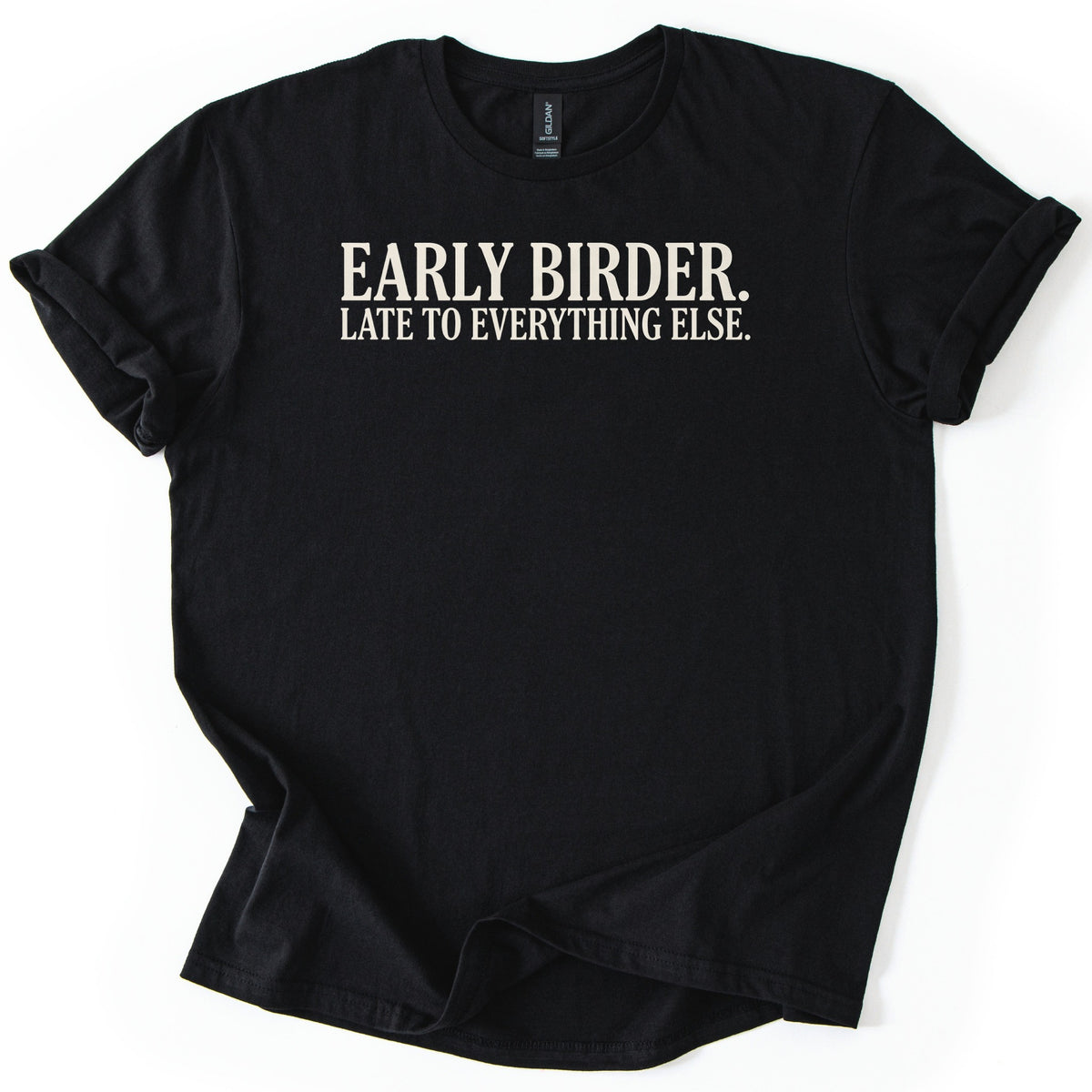 Early Birder Comfort Colors T-shirt in Black, laid flat. Cream serif capital letters across the chest read EARLY BIRDER. LATE TO EVERYTHING ELSE. The shirt lies on a white background with its short sleeves rolled up.