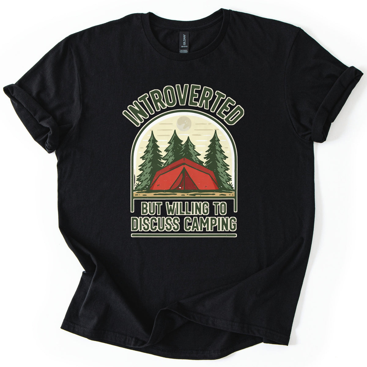 Introverted Camping Comfort Colors T-shirt in Black, laid flat. An arched badge shows a red tent among green pine trees under a pale moon, with INTROVERTED curved above and BUT WILLING TO DISCUSS CAMPING below in cream letters. The shirt lies on a white background.