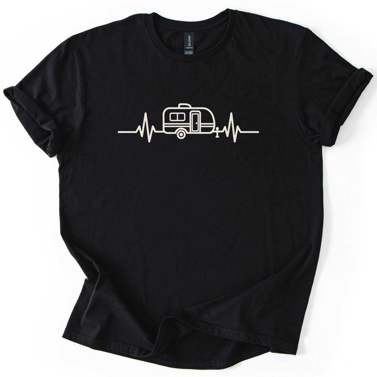 Camper Heartbeat Comfort Colors T-shirt in Black, laid flat. A cream line drawing of a small camper trailer with a window, door, wheel and hitch jack sits in the middle of a heartbeat line across the chest, with no words. The sleeves are cuffed on a white background.