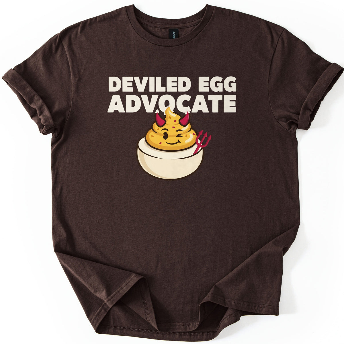 Deviled Egg Advocate Comfort Colors T-shirt in Dark Chocolate, laid flat. Bold cream text reads Deviled Egg Advocate above a cartoon deviled egg with red devil horns, a wink, and a small red pitchfork. The shirt has cuffed sleeves and lies on a white background.