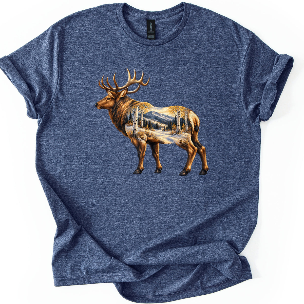 Aspen Pass Elk Comfort Colors T-shirt in Heather Navy, laid flat. A realistic bull elk stands facing left, its body filled with a snowy mountain trail lined with white aspens in golden leaves and dark pines. No words. The shirt lies on white, hem folded at an angle.