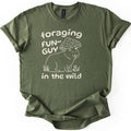 Foraging Fun-Guy Capybara Comfort Colors T-shirt in Military Green, laid flat. A cream line drawing of a winking capybara with its tongue out, wearing a spotted mushroom cap and sitting in grass by tiny mushrooms, with the words foraging FUN-GUY in the wild. Sleeves rolled, on white.
