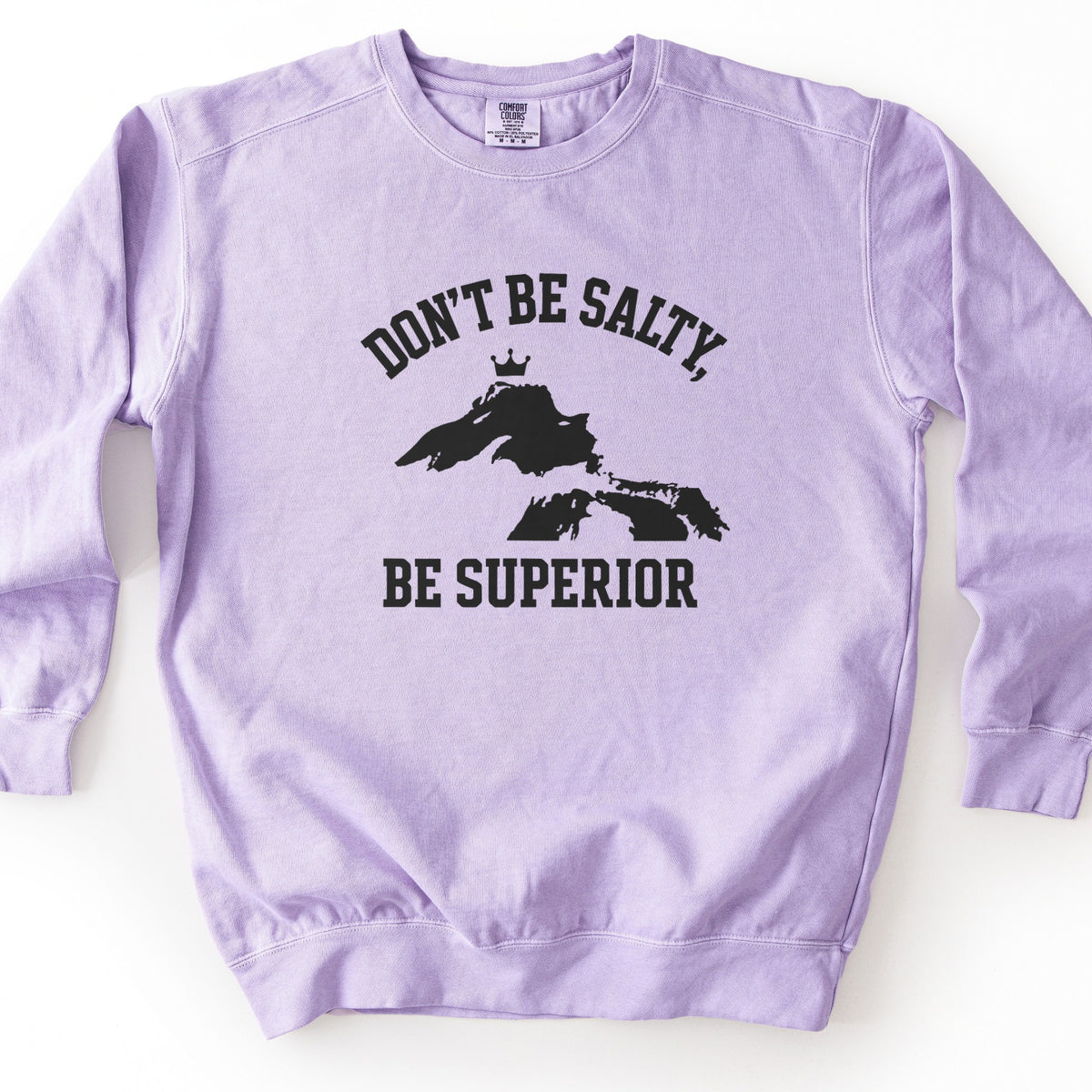 Be Superior Comfort Colors crewneck sweatshirt in Orchid, laid flat. Black print of the words Don't Be Salty, arched above a silhouette of Lake Superior topped with a small crown, with Be Superior below. Laid on a white background.