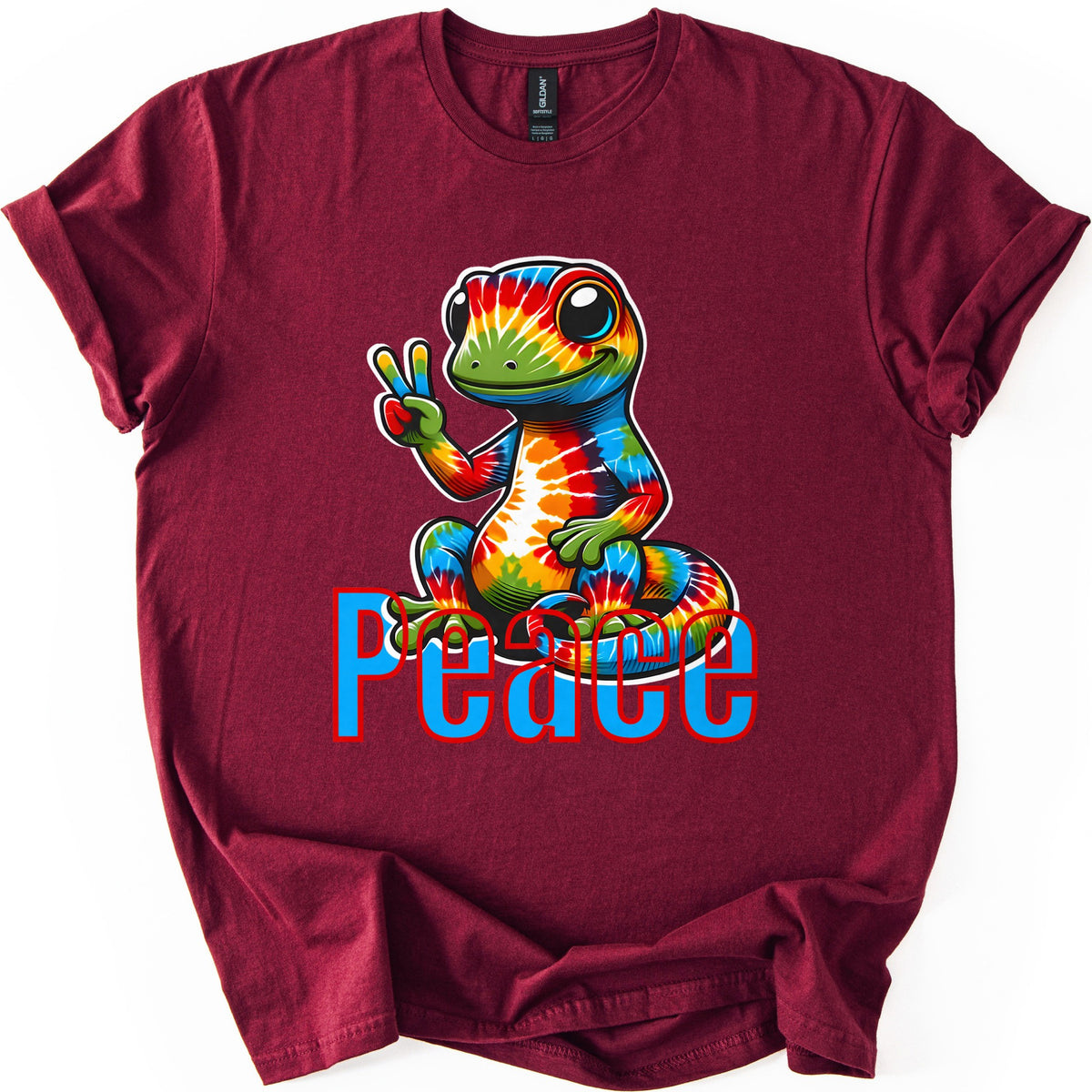 Rainbow Lizard Peace Comfort Colors T-shirt in Maroon, laid flat. A smiling cartoon lizard with tie-dye rainbow skin sits on its curled tail and flashes a peace sign above the word Peace in blue letters outlined in red. Cuffed sleeves on a white background.